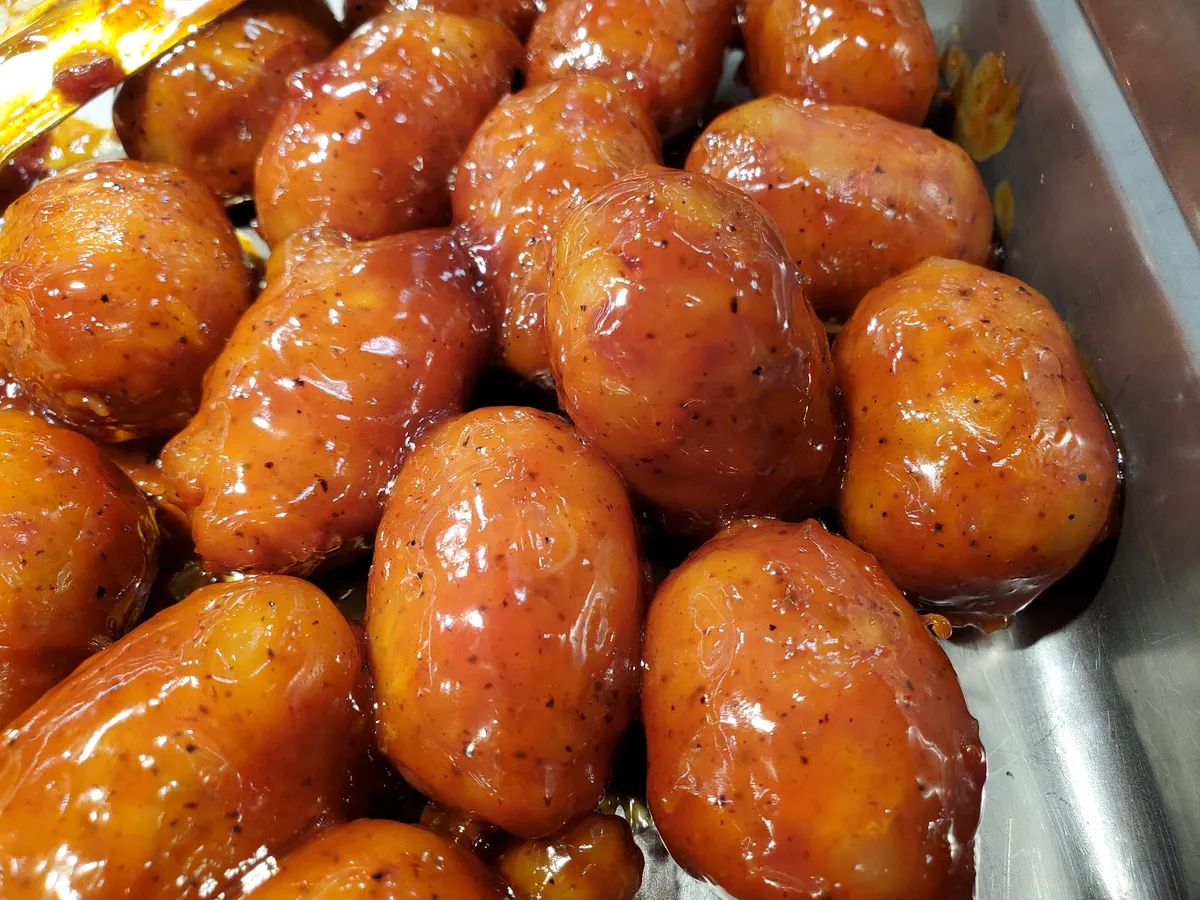 Glazed sausage-like food items in a serving tray